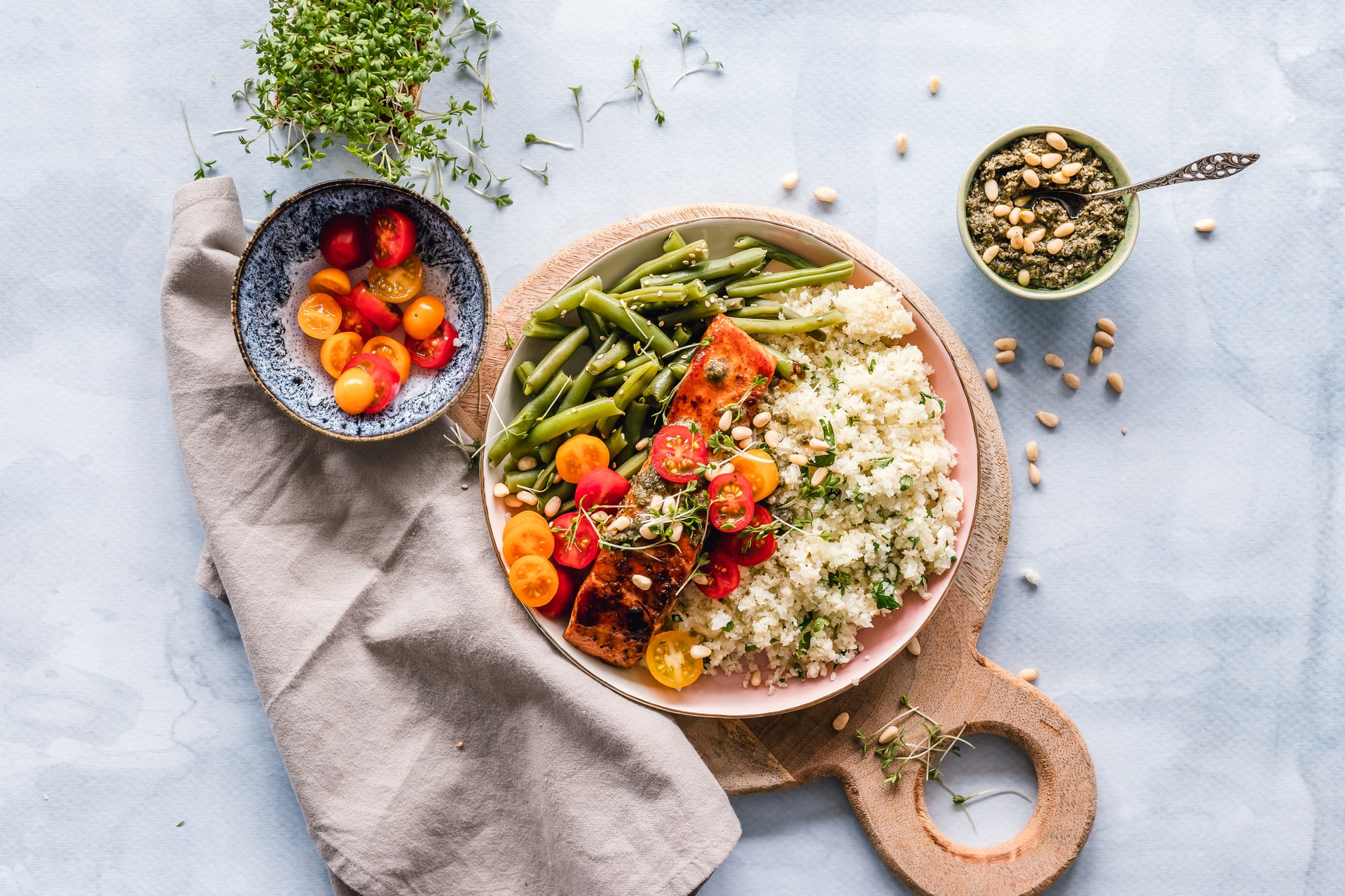 Salmon, rice, tomatoes, green beans and pine nuts on a plate