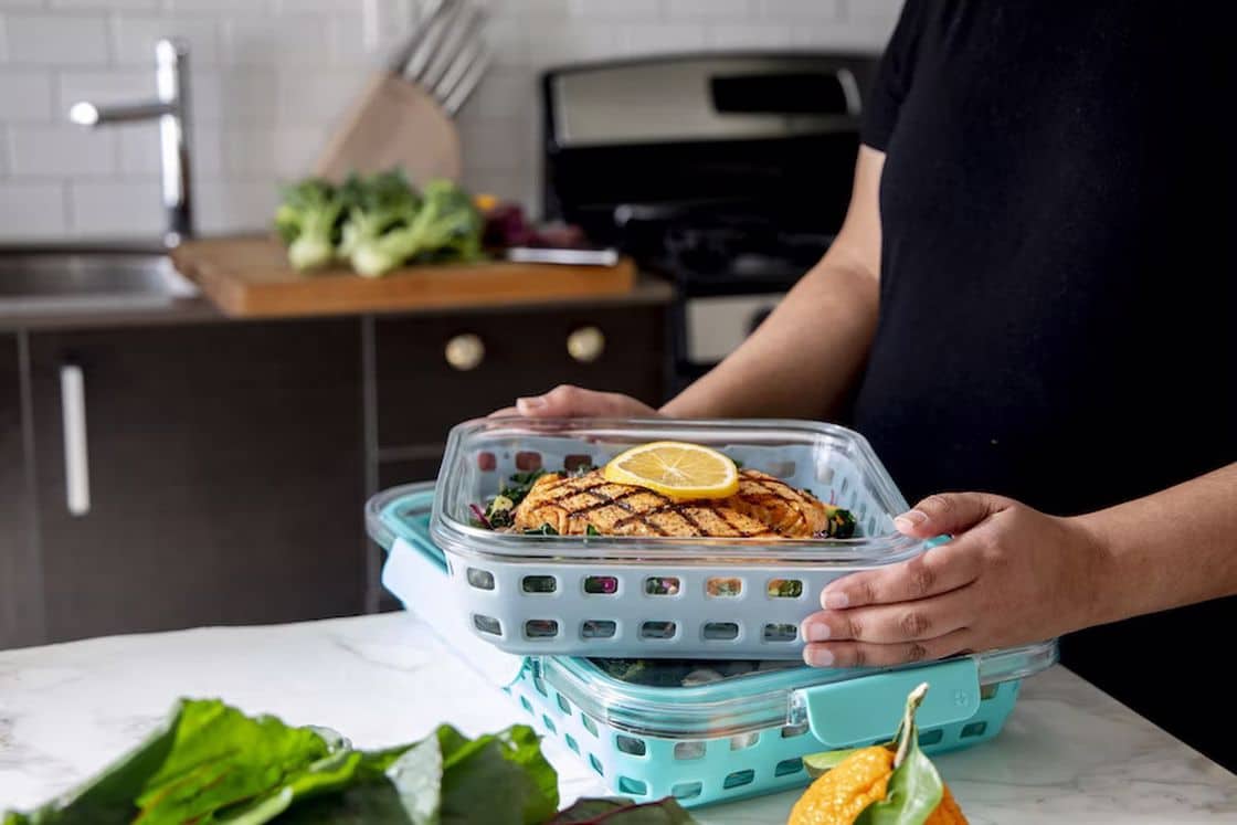 Woman putting her chicken meal prep in storage containers