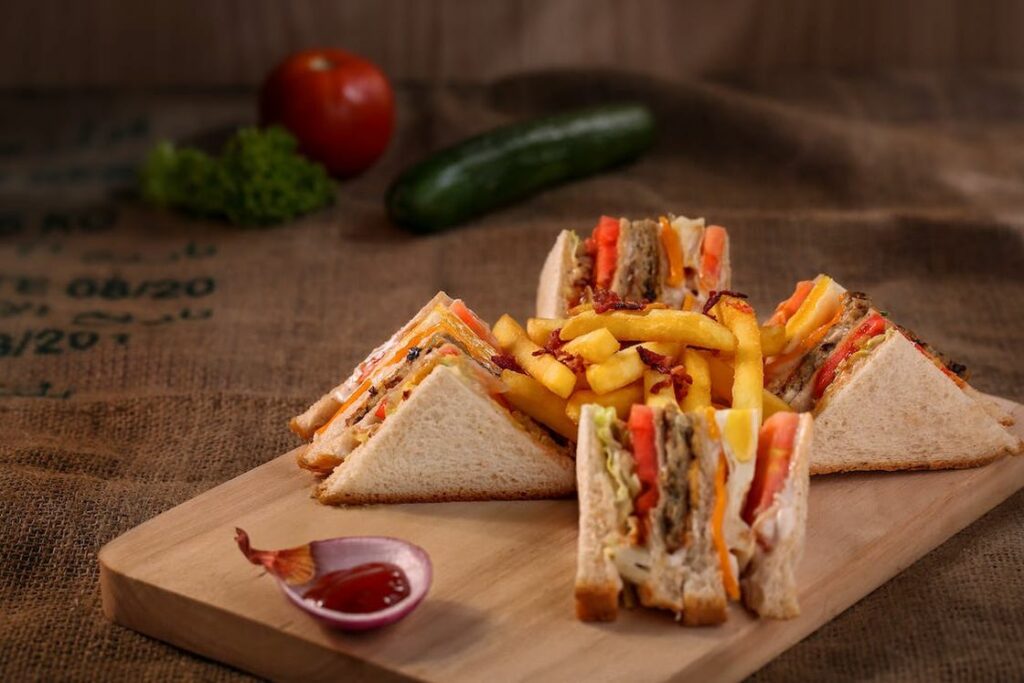Prepped sandwiches with fries and ketchup in a wooden board