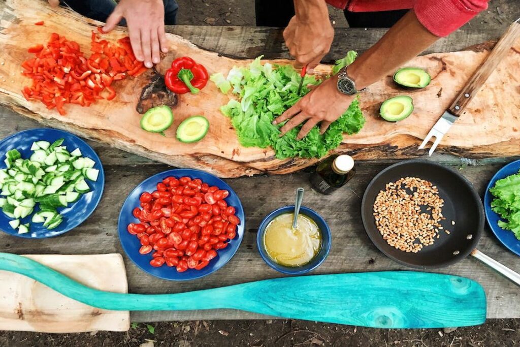 Two people cutting vegetables and preparing ingredients for a meal