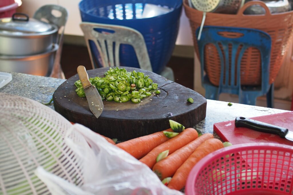 Sliced green peppers on top of a brown wooden chopping board on top of a marbled table