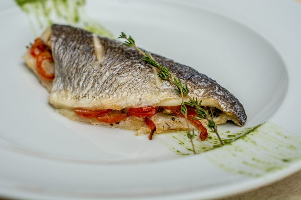 Sea bass fish dish with herbs on top served on a white plate