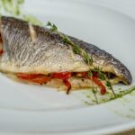 Sea bass fish dish with herbs on top served on a white plate
