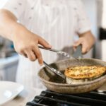 A chef cooking fish on a frying pan in the kitchen