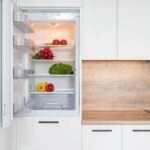 Door of a refrigerator is open and shows vegetables stored inside