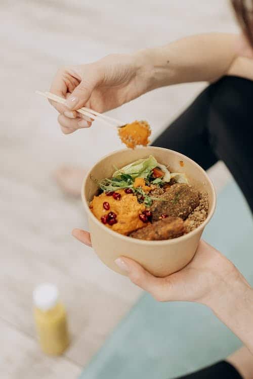 Woman using a chopstick to grab food from her bowl