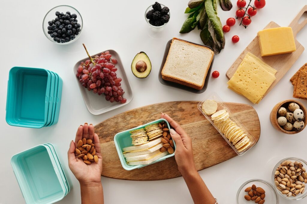 A person preparing food in a turquoise-colored food container near a brown wooden board on top of a white surface