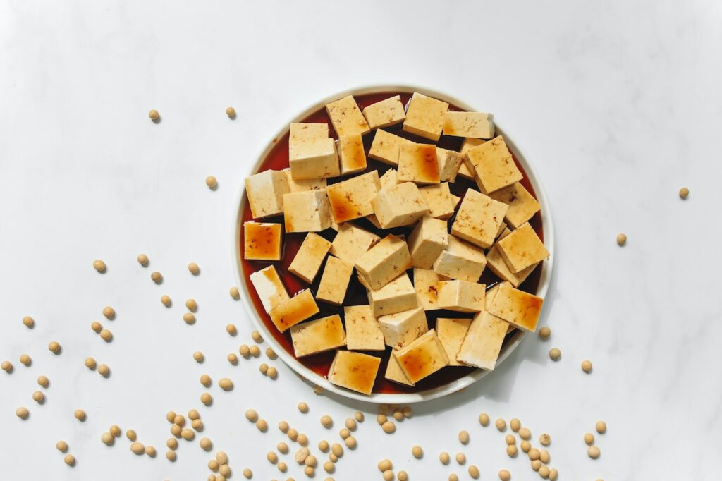 Sliced tofu with brown sauce on a white plate on top of a white surface