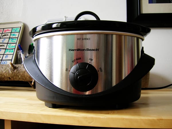 A silver colored slow cooker cooking meal in the kitchen