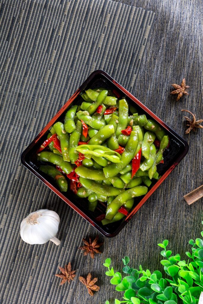 A bunch of green edamame served in a wooden plate.