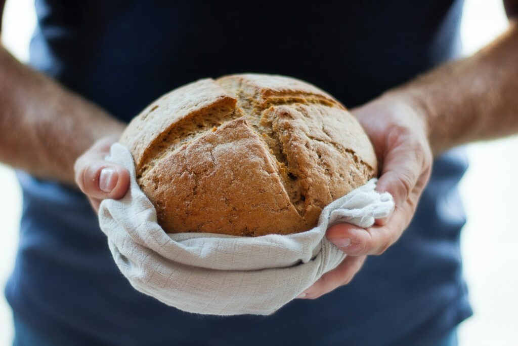 A man holding a bread with a bread bag