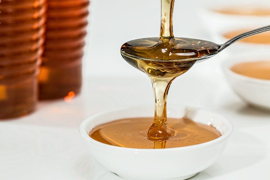 A honey syrup dripping on a spoon and a small bowl