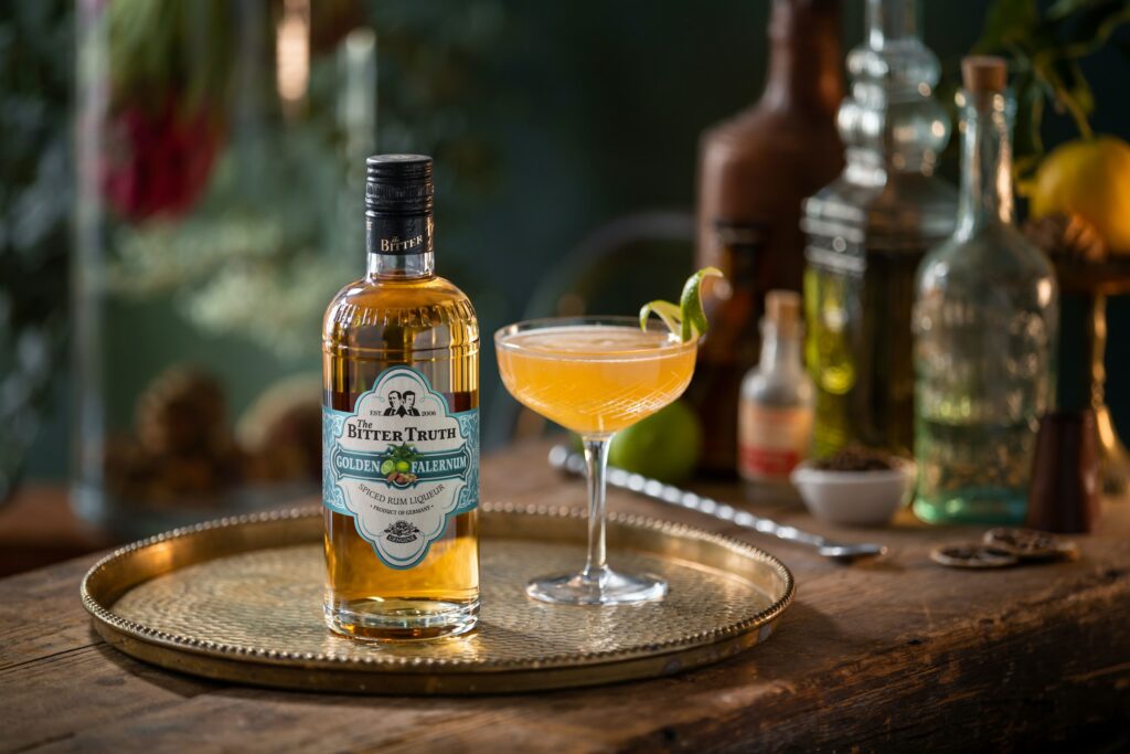 A bottle of golden falernum spiced rum liqueur with a glass of cocktail