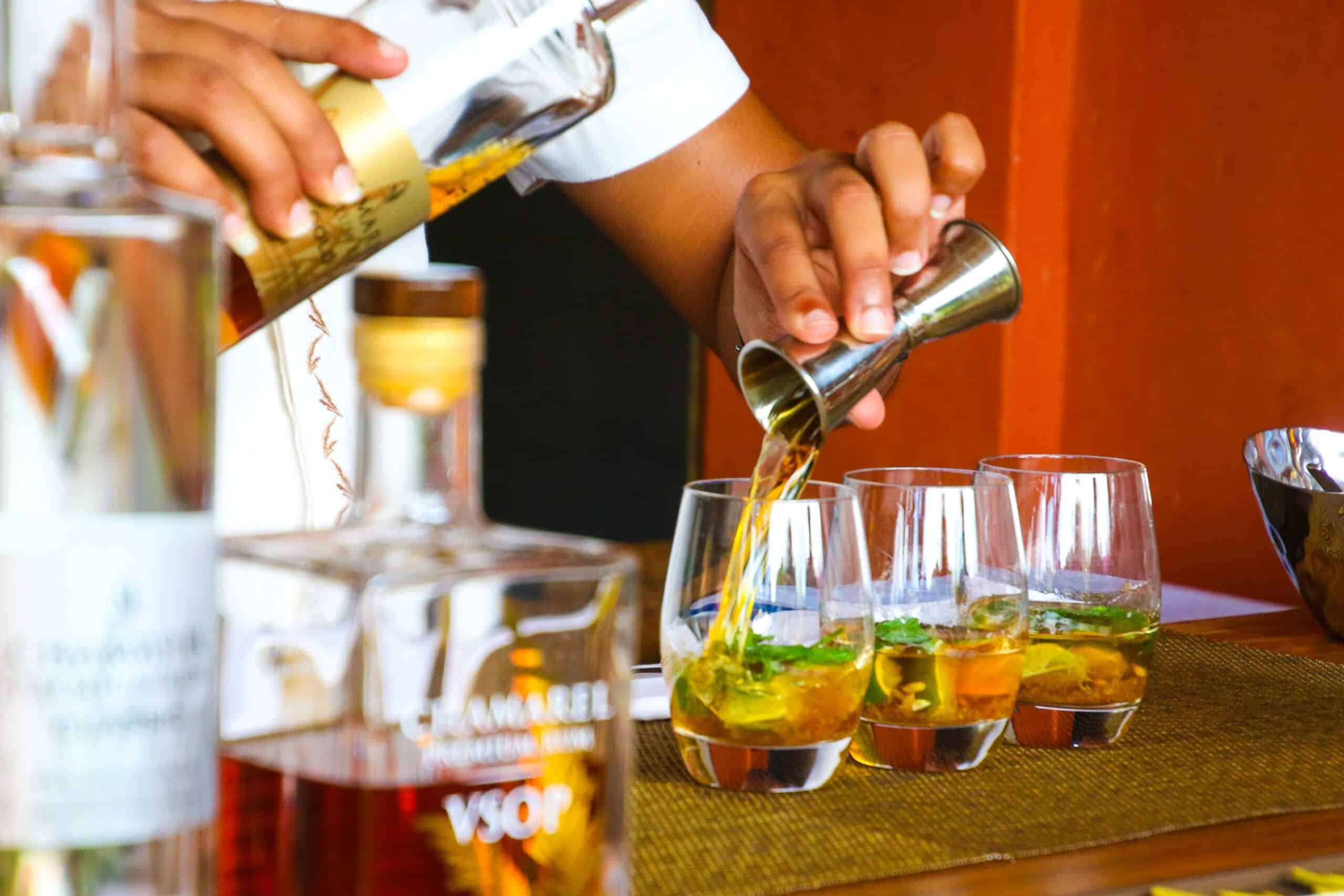 A bartender pouring liquor on cocktails