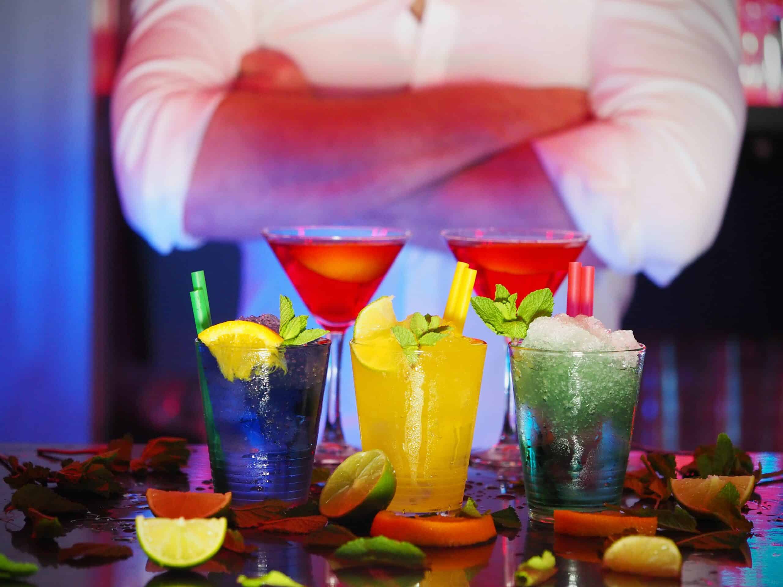 Three different colored cocktails in front of a bartender
