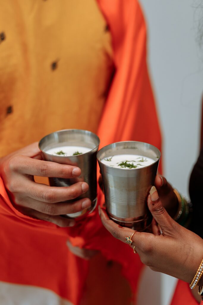 Two persons holding two cups of buttermilk