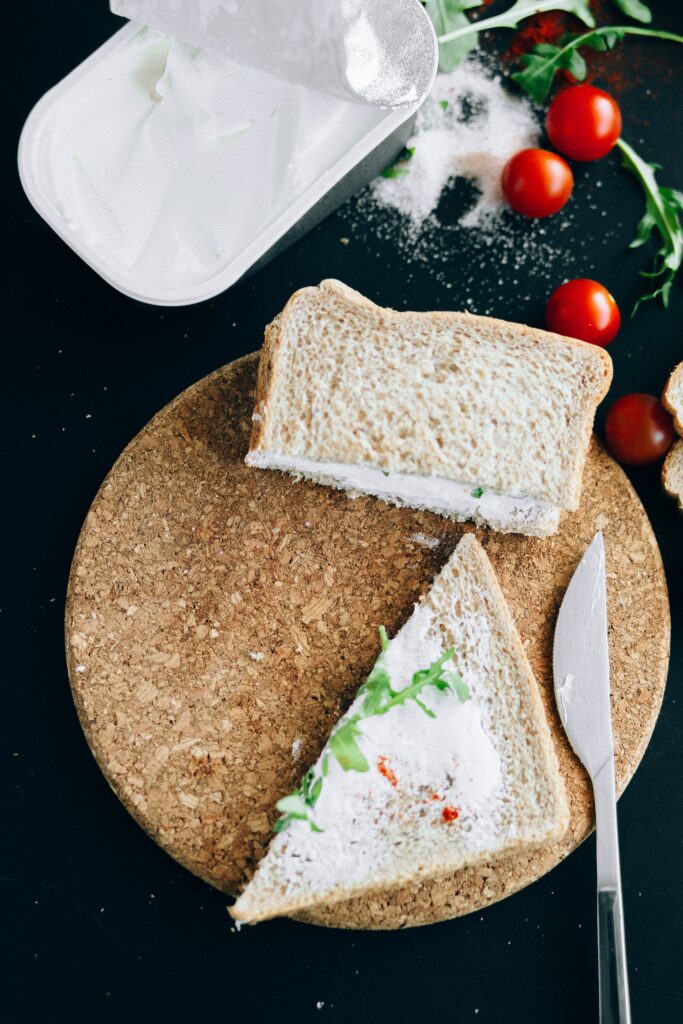 A tub of cream cheese and a sliced bread with cream cheese