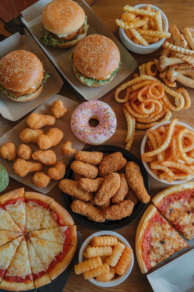 Different unhealthy foods like pizza, burger, and fries 