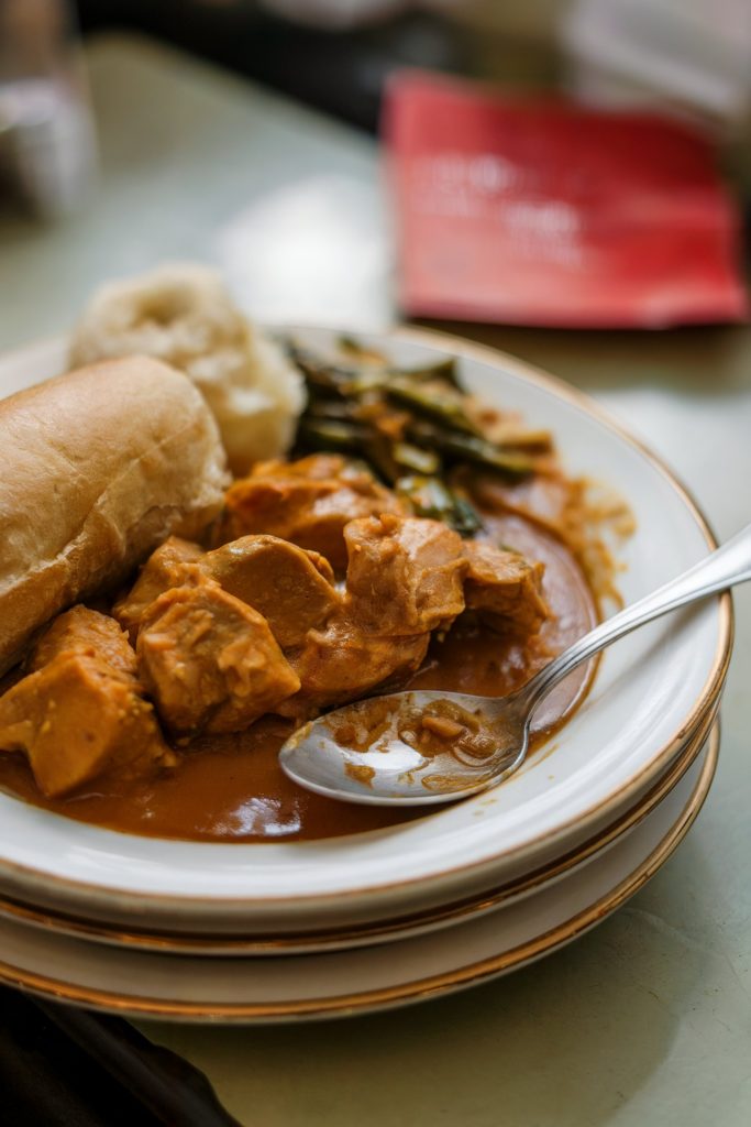 A chicken curry with spoon and bread