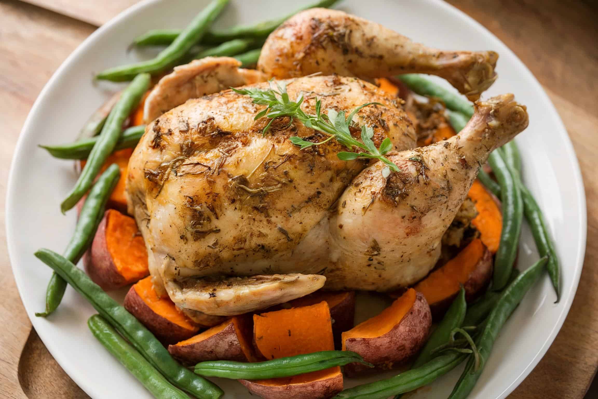 A whole baked chicken with beans and sweet potatoes