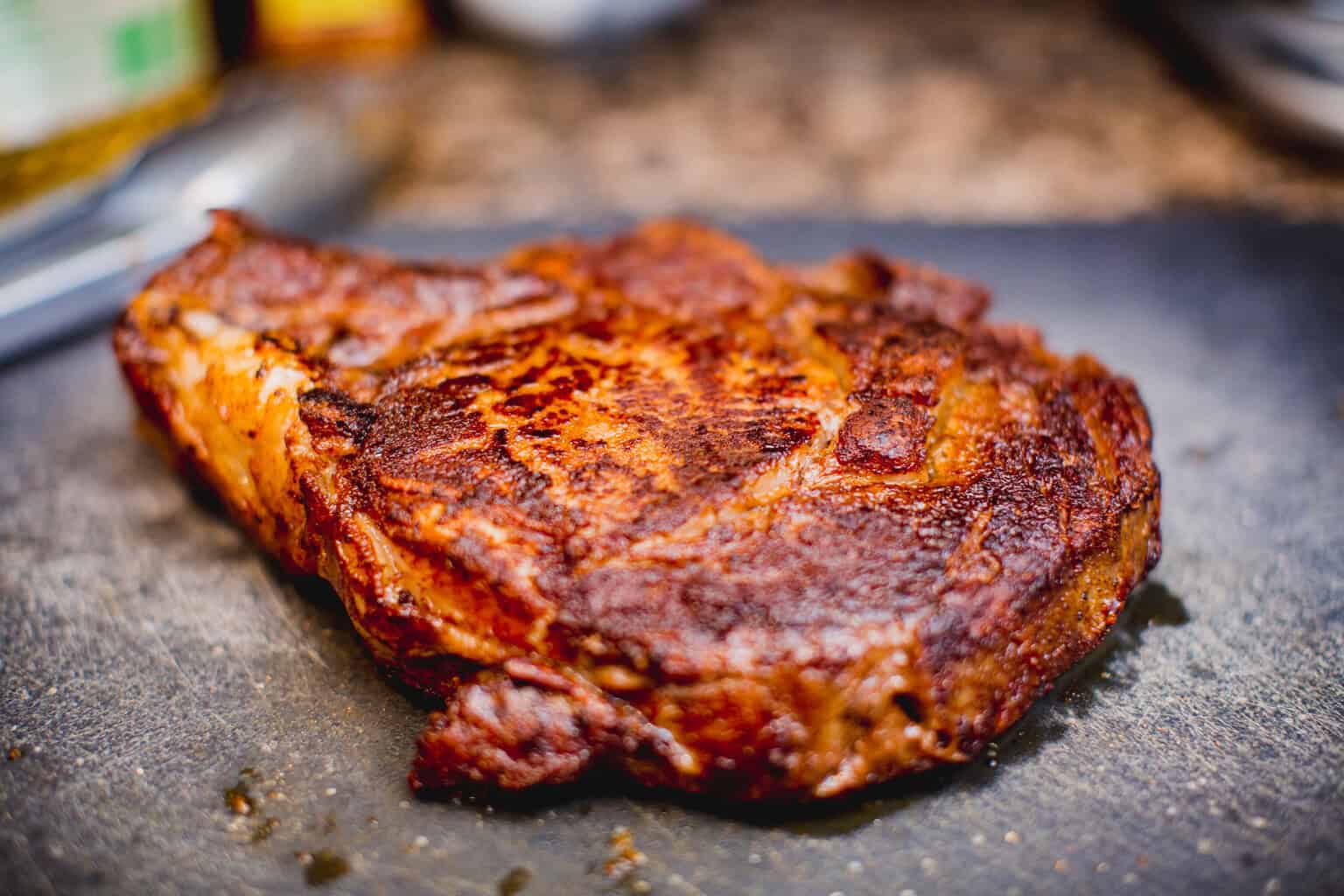 Perfectly seared rib-eye steak resting on a cutting board