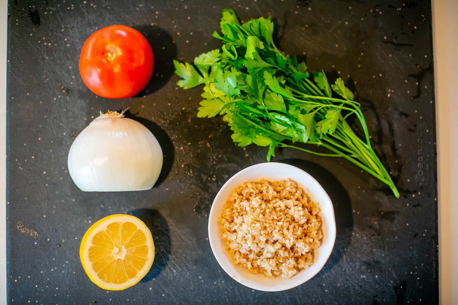 Ingredients for tabbouleh: fresh parsley, onion, tomato, bulgur, and lemon