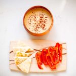 Hummus served with pita bread and sliced red bell peppers