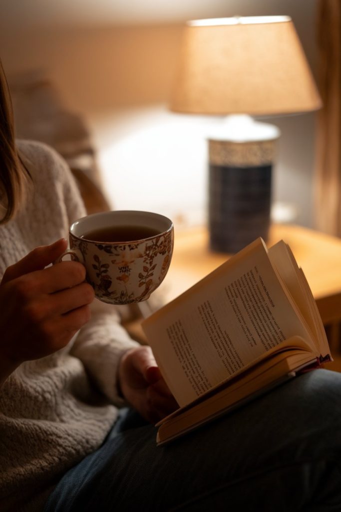 A person reading a book while drinking tea