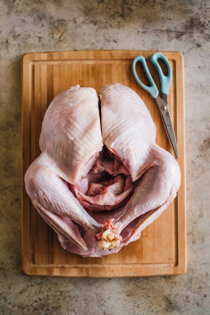A whole turkey cut in half with scissors beside it