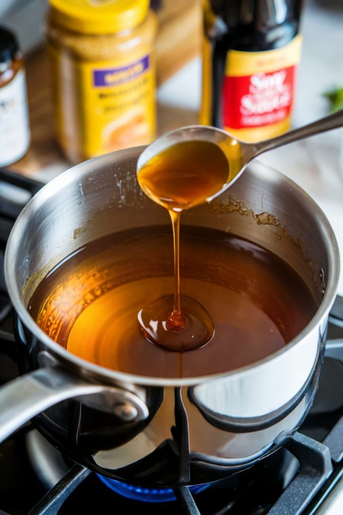A pot with honey glaze with a spoon scooping some of it