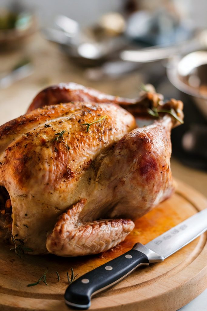 A whole cooked turkey on chopping board with a knife beside it