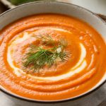 A creamy carrot fennel soup with a sprinkle of fresh dill on top