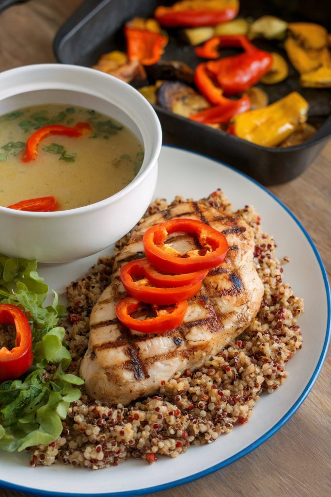 A chicken with quinoa and bell pepper on it