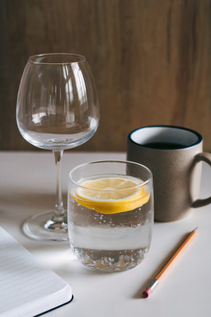 A wine glass, a coffee, and a water with lemon in it