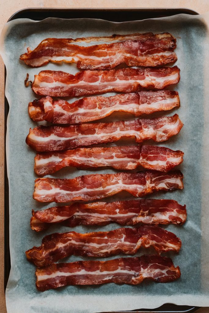 Cooked bacon strips lined in a single layer on a parchment paper
