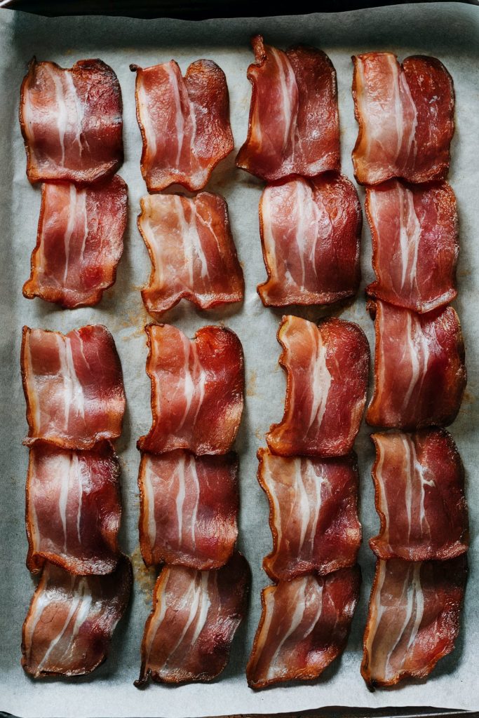 Small cut bacon pieces on a baking tray with parchment paper