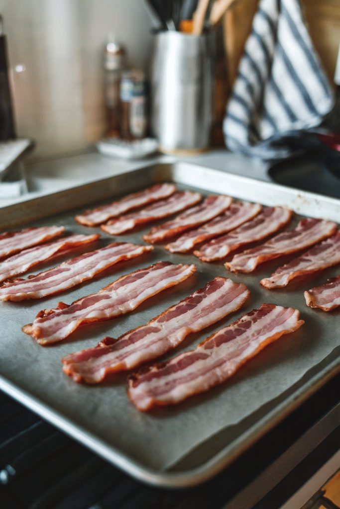 Uncooked cut of bacon strips placed on a baking tray