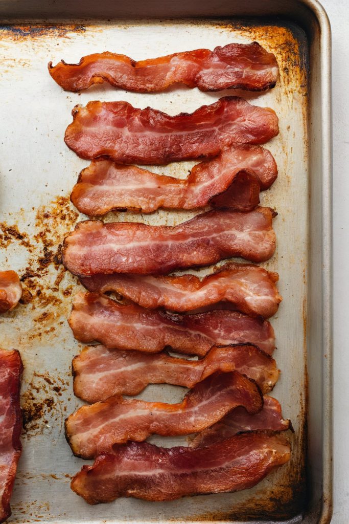 Turkey bacon strips lined up on a baking tray