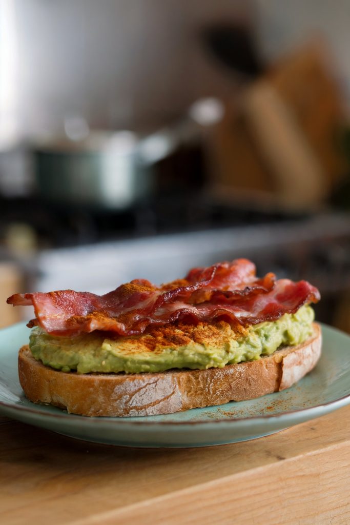 A bread with avocado topped with crispy bacon