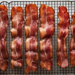 Bacon strips lined up on a cooling rack
