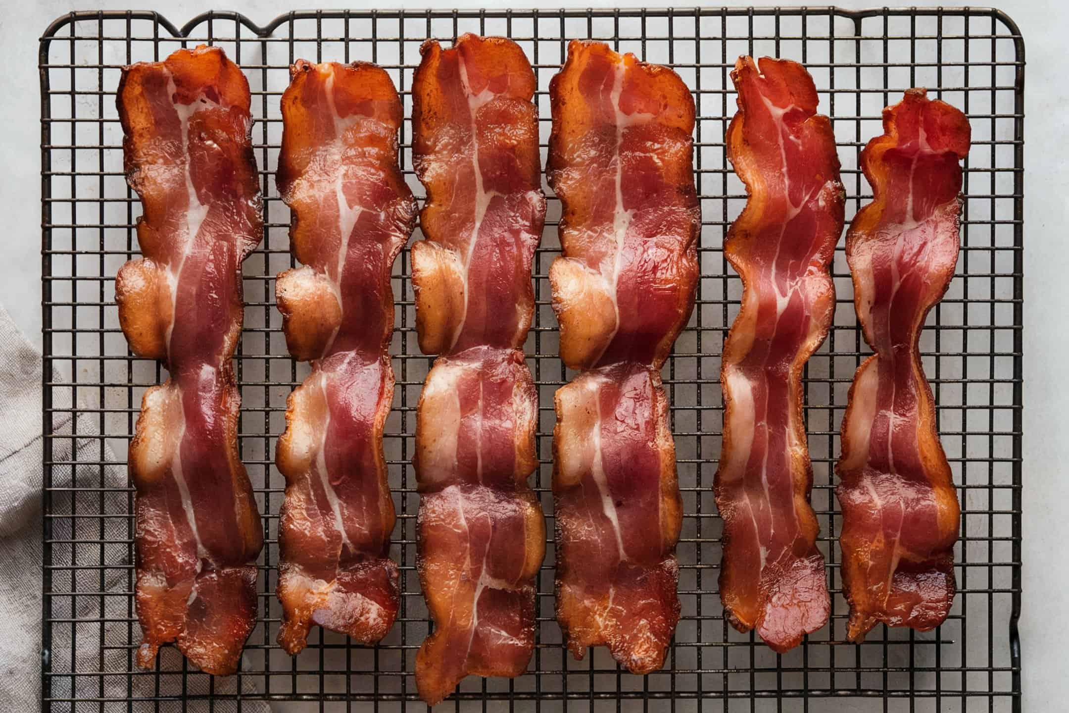 Bacon strips lined up on a cooling rack