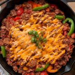 A savory meal of meat with cheese on top placed on a skillet