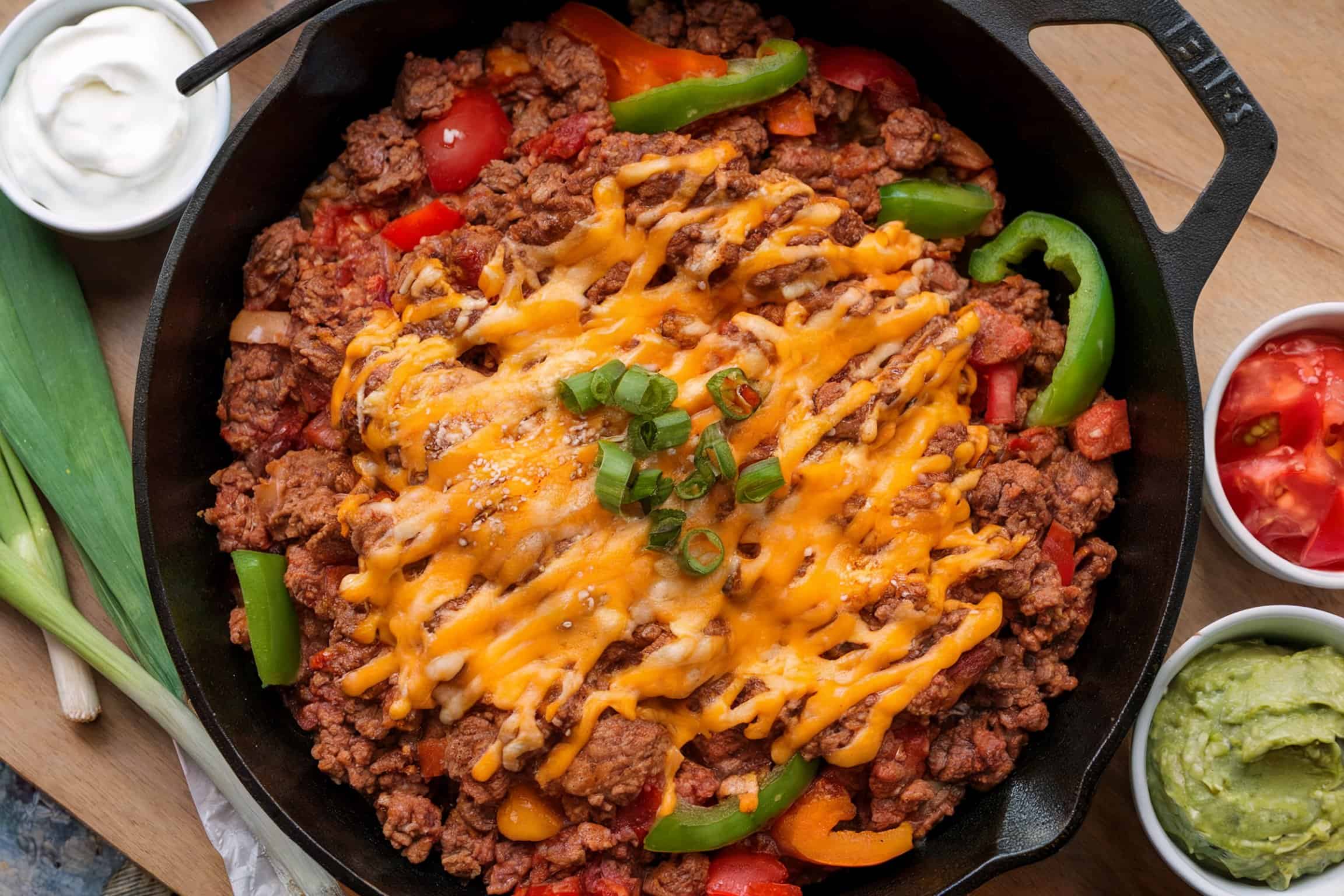 A savory meal of meat with cheese on top placed on a skillet