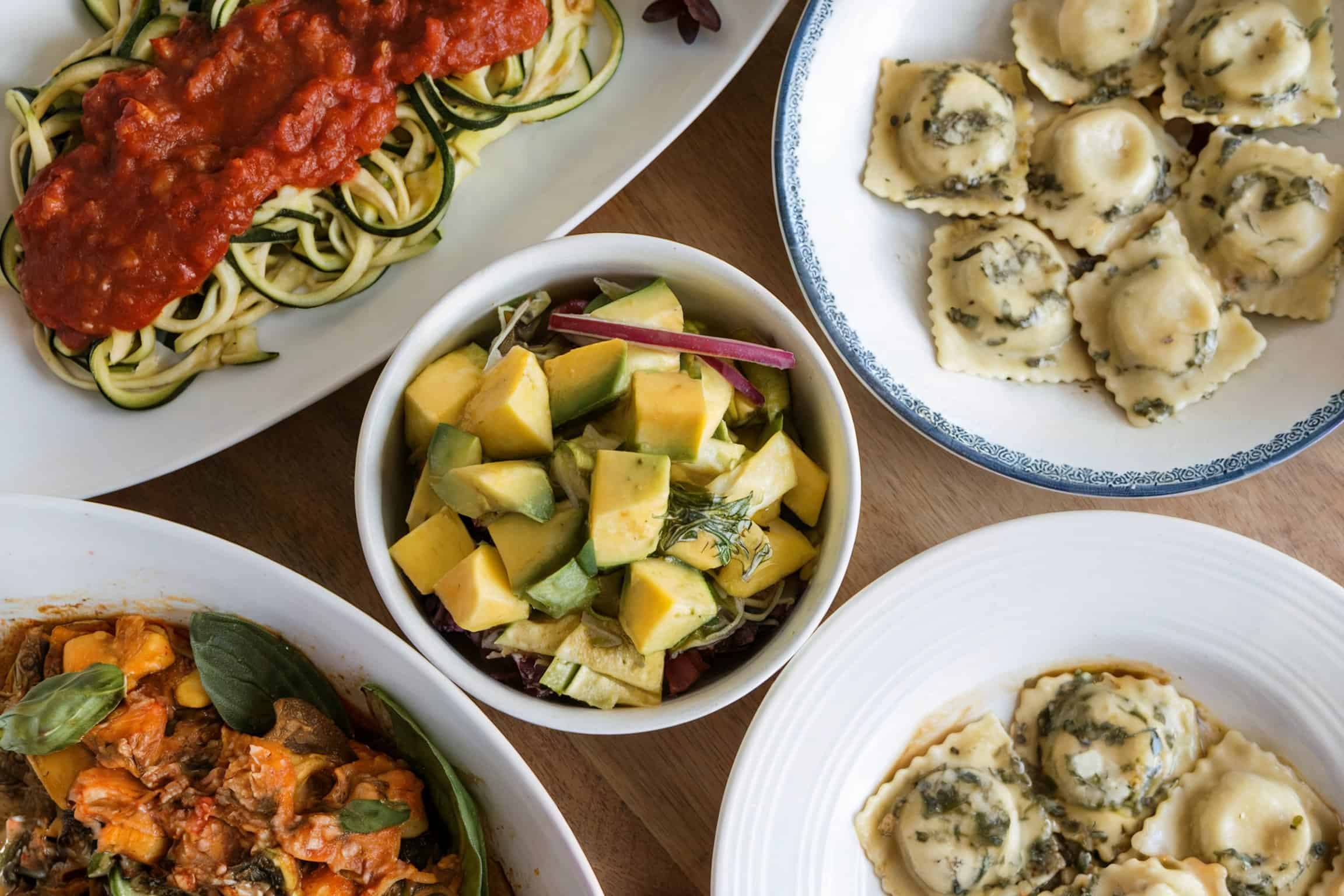 Different types of meal like xucchini Noodles with marinara, gnocchi with pesto cream, and mango and avocado salad