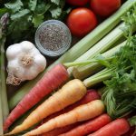 Asparagus, carrots, garlic, tomatoes. chia seeds and some leafy greens on a table