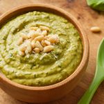 A creamy pesto sauce in a wooden bowl