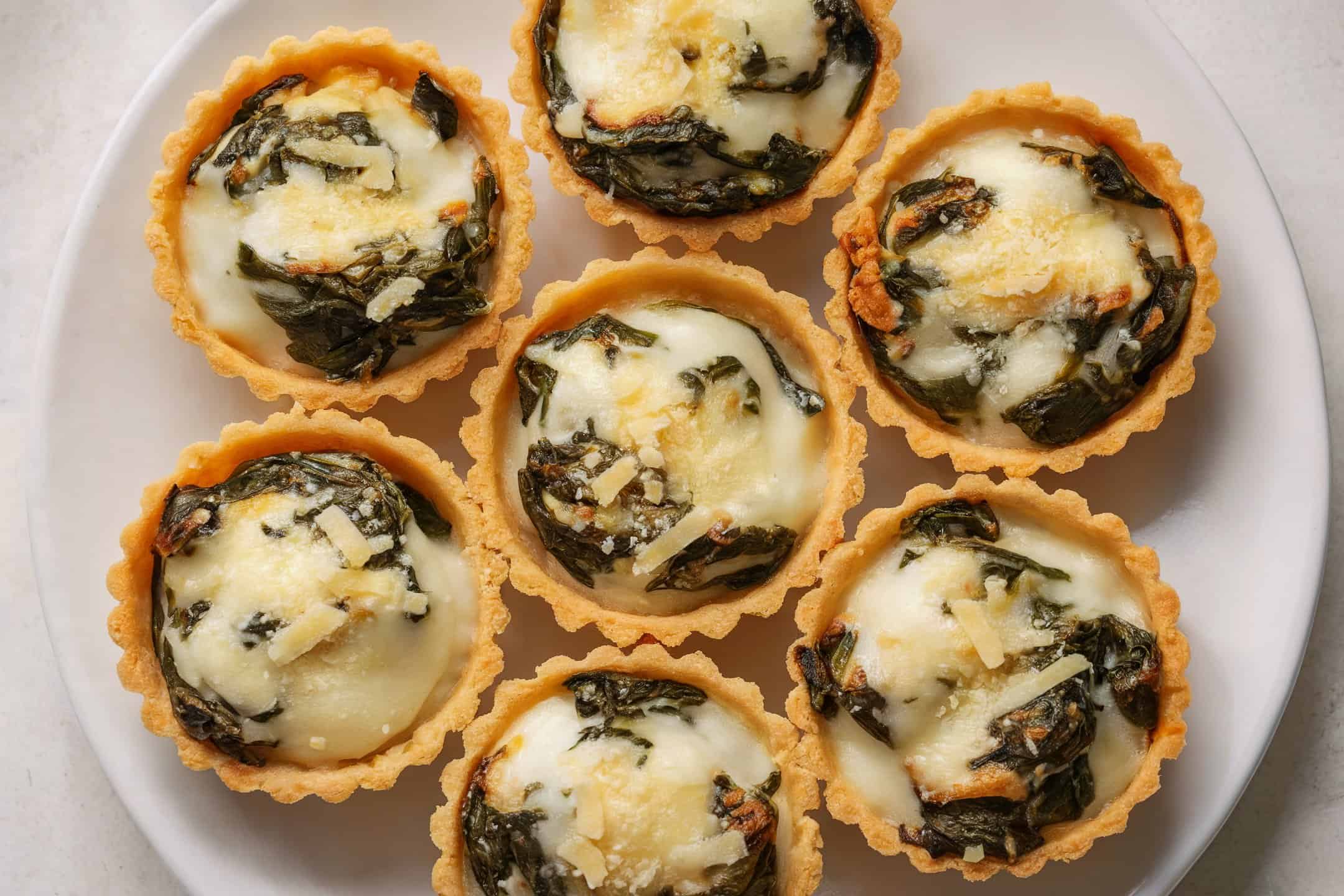 A plate of mini cheese and spinach savory tarts