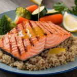 A plate of grilled salmon with quinoa and steamed vegetables