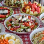 A table with various salads like Greek salad, Caesar salad, and a few more