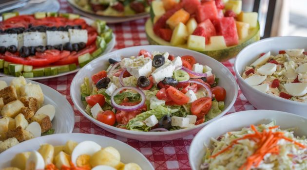 A table with various salads like Greek salad, Caesar salad, and a few more